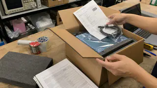 Packed engineering test equipment with cables and documentation review on a workbench